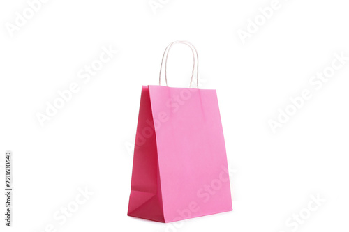 Single blank shoppong bag standing on isolated white background. Pink paper packet reflecting studio light. Black friday sale concept. Close up, copy space for text.