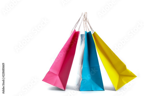 Many blank paper shopping bags of different colors, pink, blue and yellow isolated on white background. Blank colorful packets. Black friday sale concept. Close up copy space.