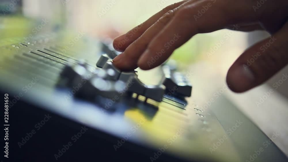 The DJ is adjusting the volume of the sound. Professional audio mixing console The DJ is adjusting the volume of the sound. Professional audio mixing console