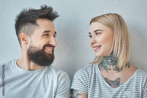 portrait of smiling couple with tattoos looking at each other