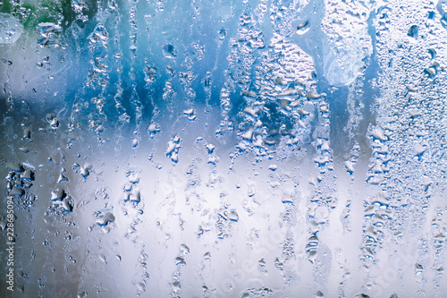 Misted glass with water drops on blue background