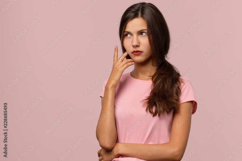 An attractive long-haired brunette girl with a serious thoughtful expression looks to the side. The concept of prudence, reflection, decision-making. It is difficult to make a choice in this situation An attractive long-haired brunette girl with a serious thoughtful expression looks to the side. The concept of prudence, reflection, decision-making. It is difficult to make a choice in this situation