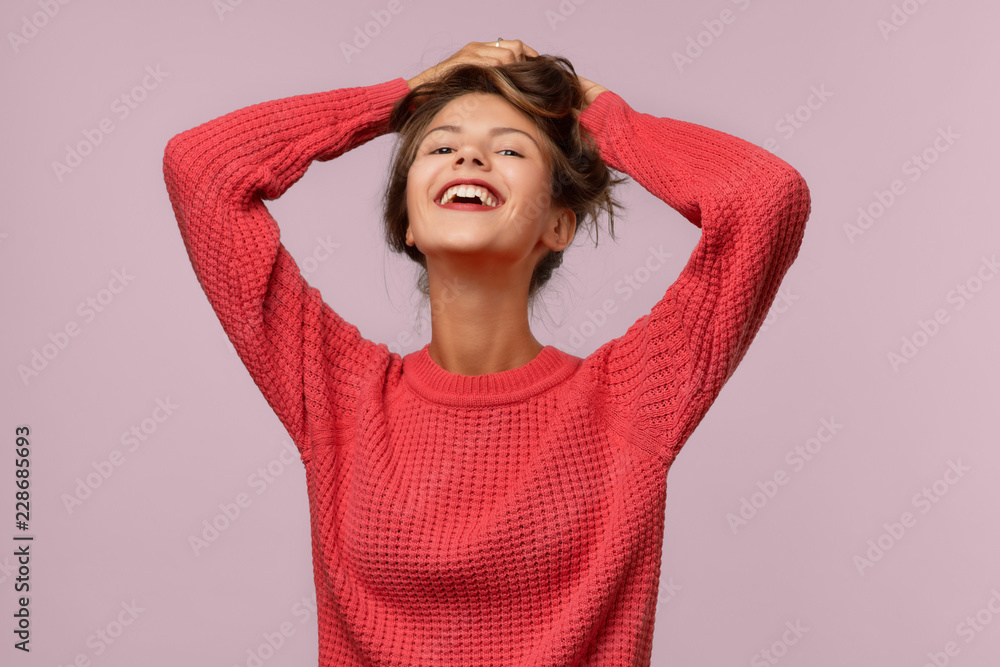 Horizontal portrait of attractive Caucasian woman in red knitted sweater. She straightens her long dark straight hair and laughs, lifting her chin up Horizontal portrait of attractive Caucasian woman in red knitted sweater. She straightens her long dark straight hair and laughs, lifting her chin up