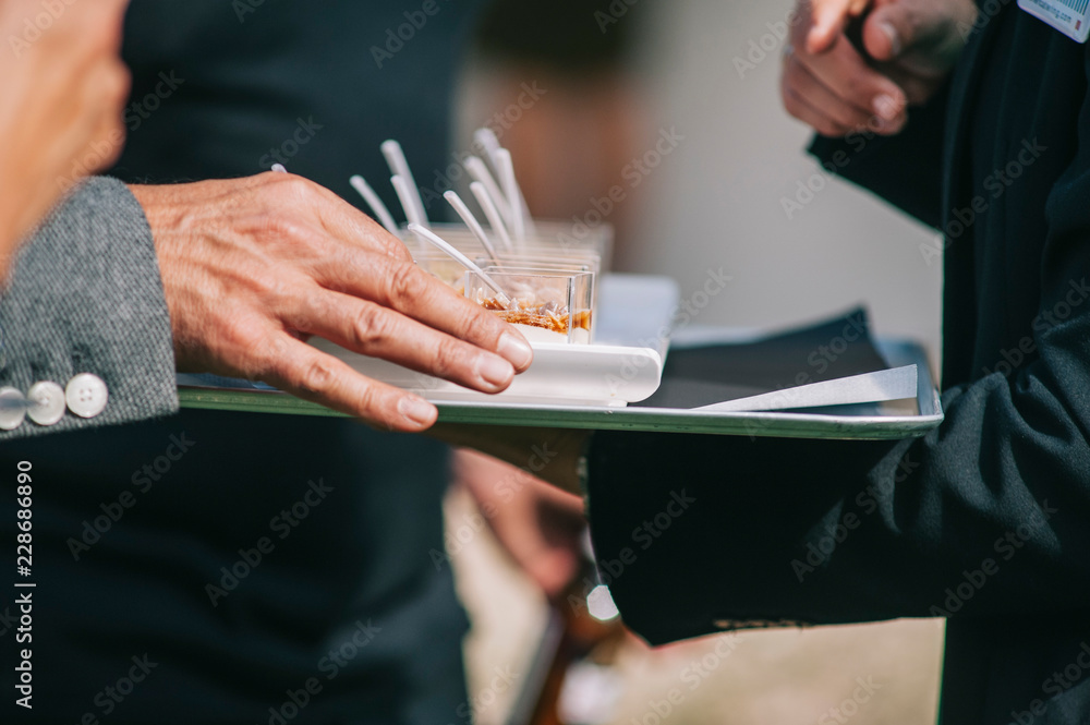 Catering service. Waiter carrying a tray of appetizers. Outdoor party with finger food, sweets.