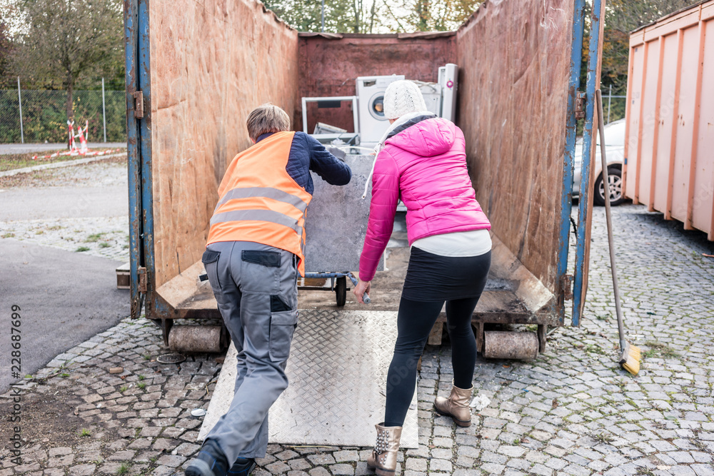 Frau und Mann geben alte Elektrogeräte auf dem Wertstoffhof ab Frau und Mann geben alte Elektrogeräte auf dem Wertstoffhof ab