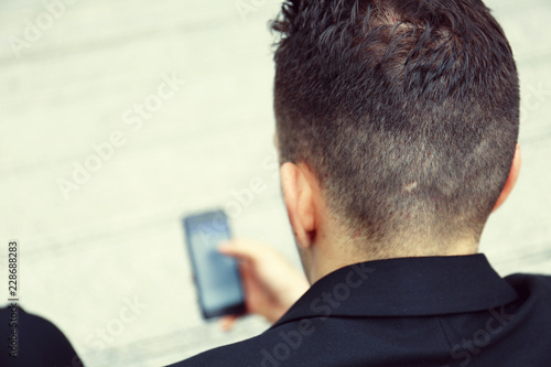 Business man looking on mobile phone on street and blur mobile phone device.
