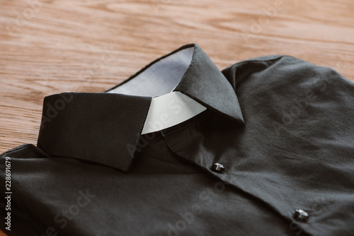 Картината върху платно close-up shot of clerical shirt with white collar on wooden surface