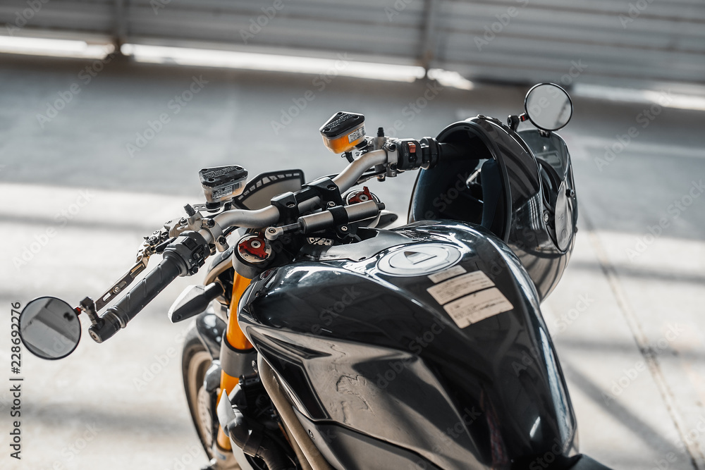 Close up of black glossy helmet at motorcycle handlebars. Urban background. Close up of black glossy helmet at motorcycle handlebars. Urban background.