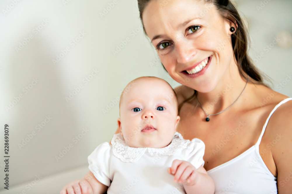 Portrait of a beautiful mother with her 2 month old baby in the bedroom Portrait of a beautiful mother with her 2 month old baby in the bedroom