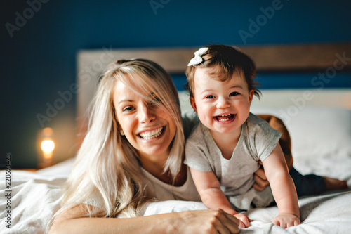 Mother Playing With Baby Daughter In Bedroom At Home photo