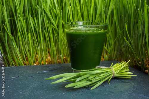 Green organic wheat grass drink over dark wood background,top view ,young grass stage.