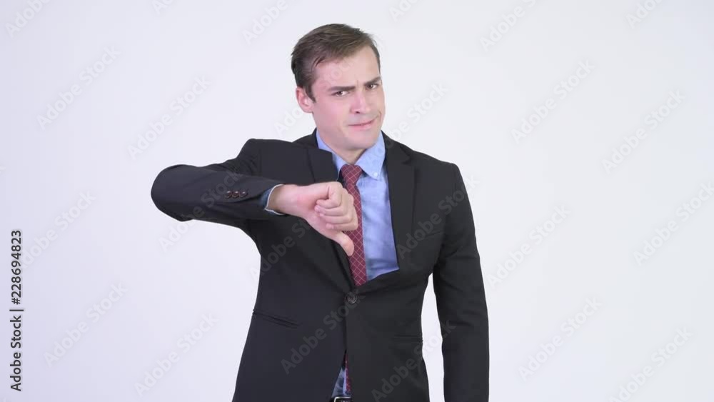 Young stressed businessman looking angry while giving thumbs down Young stressed businessman looking angry while giving thumbs down