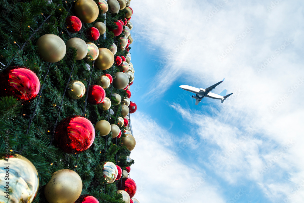 Fototapeta premium Decorated Christmas tree and airplane in blue sky