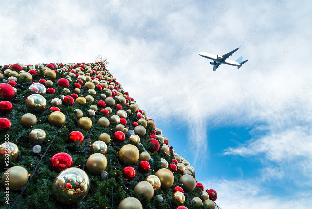 Obraz premium Decorated Christmas tree and airplane in blue sky