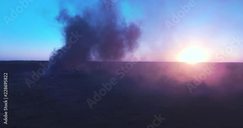clouds of smoke come from an object burning in the field