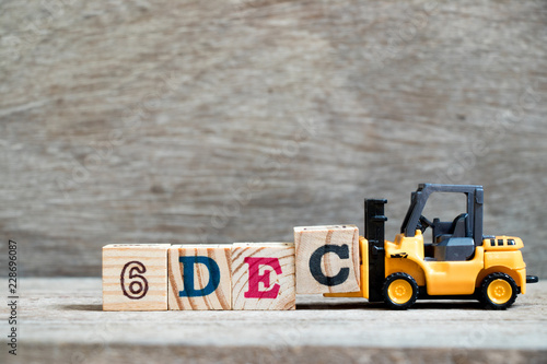 Toy forklift hold block c to complete word 6dec on wood background (Concept for calendar date 6 in month December) photo