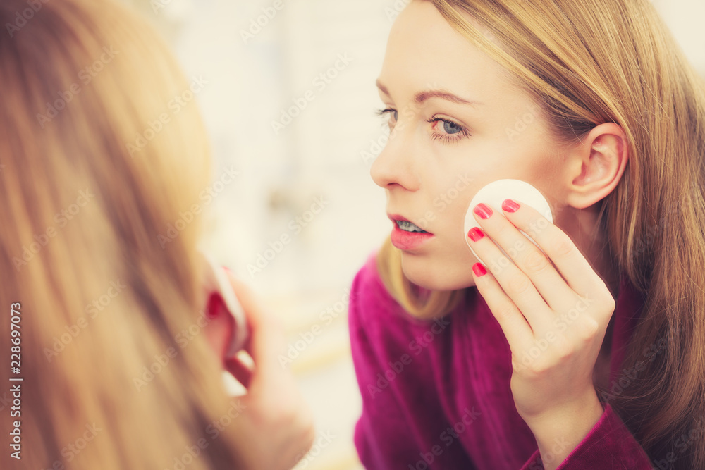 Woman using cotton pad to remove make up Woman using cotton pad to remove make up