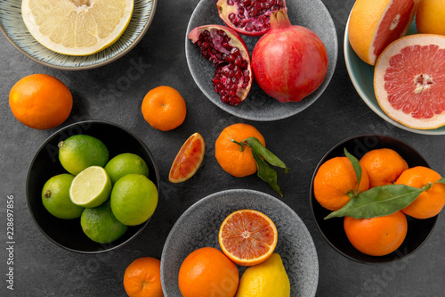 food, healthy eating and vegetarian concept - close up of citrus fruits in bowls on stone table