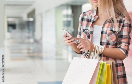 Woman texting on smartphone while shopping in mall
