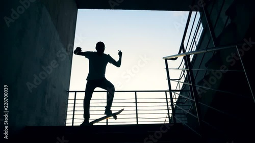 A person jumps on his board in a staircase and fails. Slow motion. photo