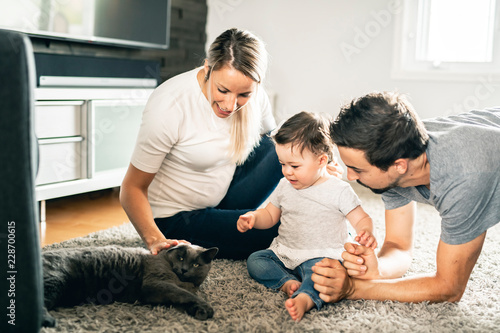 Family mother, father, child daughter at home play with cat