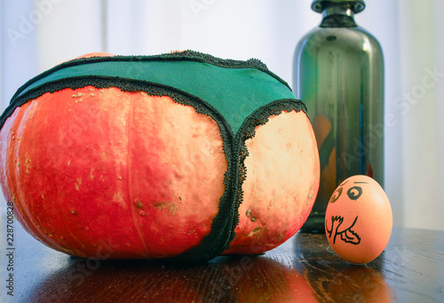 An egg staring lustfully, lecherously at pumpkin's bottom, backside, dressed in panties. Funny eggs Faces, drawnigs on eggs. photo