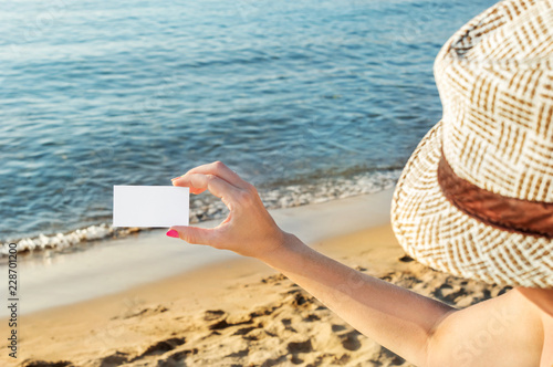 Woman in hat holding blank card at sea beach. © igorkol_ter