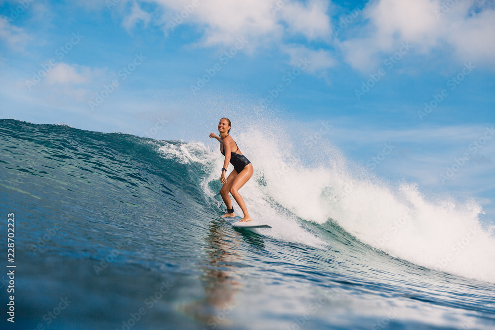 Surfer girl on blue wave. Woman during surfing