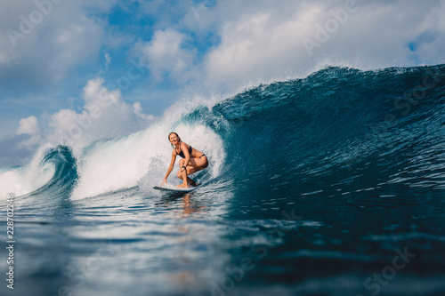 Surf girl at surfboard on barrel wave. Woman in ocean during surfing