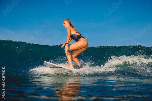 Young surfer girl with surfboard on wave.