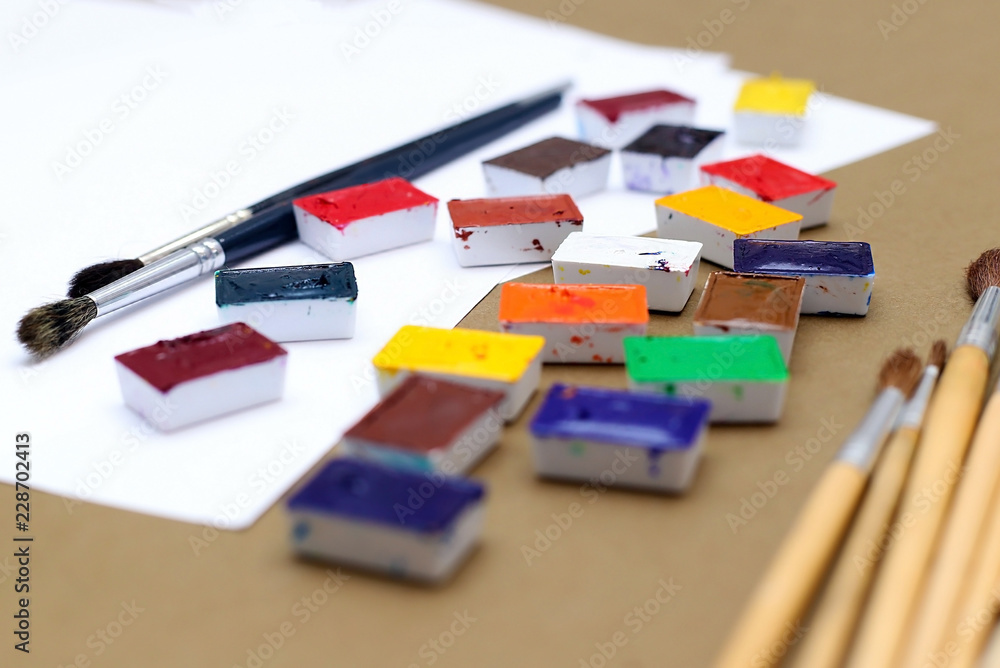 Obraz premium Bright palette of watercolor paints a white sheet to go close-up. On a bright background. Copy space.