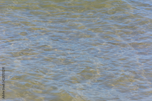 the undulating surface of the clear sea water on the shallows. the sand at the bottom