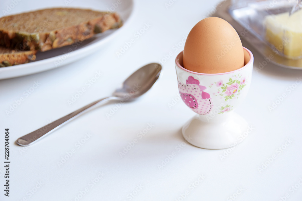 Egg in a cup with spoon, butter and bread Egg in a cup with spoon, butter and bread