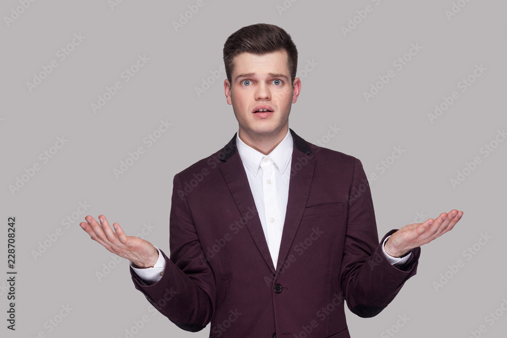 How you did this? Portrait of confused handsome young man in violet suit and white shirt, standing, looking at camera with raised arms and asking. indoor studio shot, isolated on grey background. How you did this? Portrait of confused handsome young man in violet suit and white shirt, standing, looking at camera with raised arms and asking. indoor studio shot, isolated on grey background.