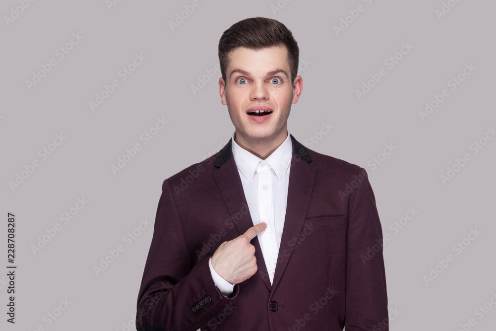 Am I winner?! Portrait of handsome amazed young man in violet suit, white shirt, standing, looking at camera, pointing himself with surprised face and asking. studio shot, isolated on grey background. Am I winner?! Portrait of handsome amazed young man in violet suit, white shirt, standing, looking at camera, pointing himself with surprised face and asking. studio shot, isolated on grey background.