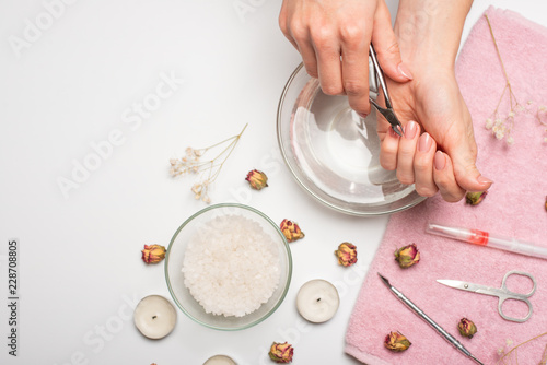 Manicure - the girl herself does, watching the nails with the help of a tool on a white background. Concept of beauty salons and nail care photo
