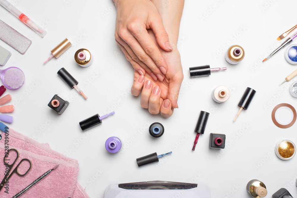 Nail care. beautiful women hands making nails painted with pink gentle nail polish on a white background. Women's hands near a set of professional manicure tools. Beauty care. A high resolution