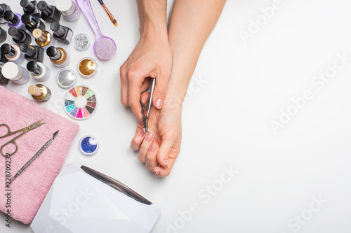 Nail care. beautiful women hands making nails painted with pink gentle nail polish on a white background. Women's hands near a set of professional manicure tools. Beauty care.top view with space. photo