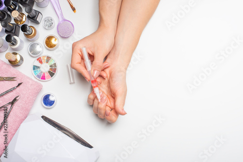 Nail care. beautiful women hands making nails painted with pink gentle nail polish on a white background. Women's hands near a set of professional manicure tools. Beauty care.top view with space. photo