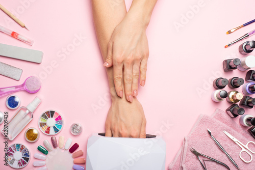 Nail care. beautiful women hands making nails painted with pink gentle nail polish on a pink background. Women's hands near a set of professional manicure tools. Beauty care