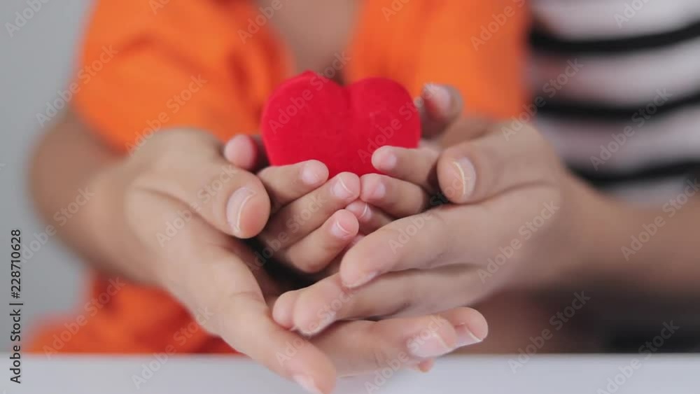 A mother with a baby showing love with holding a red heart. A mother with a baby showing love with holding a red heart.