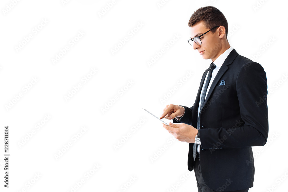 Business man, in a suit and glasses, working on a digital tablet, standing on a white background Business man, in a suit and glasses, working on a digital tablet, standing on a white background