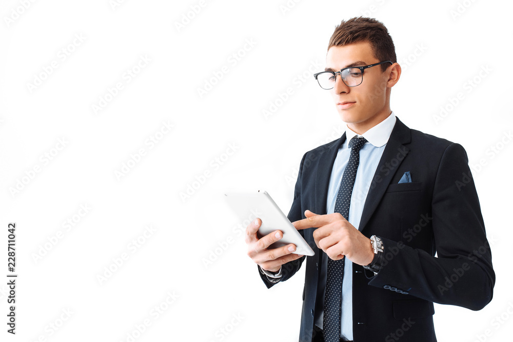 Business man, in a suit and glasses, working on a digital tablet, standing on a white background Business man, in a suit and glasses, working on a digital tablet, standing on a white background