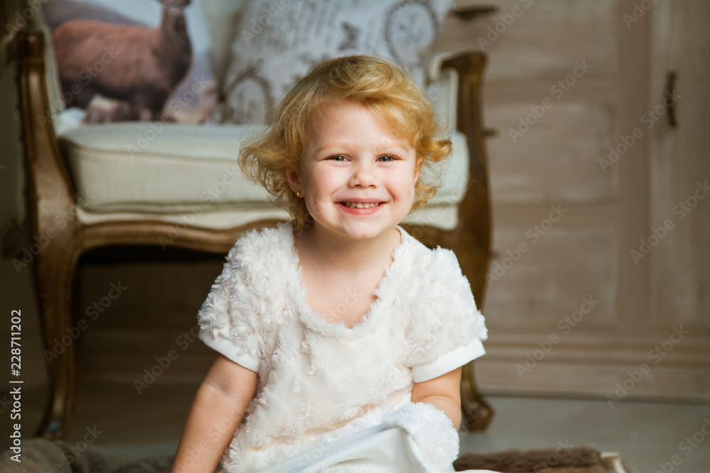 Fototapeta premium little happy girl sits in an armchair and waits for gifts for the holiday of Christmas and New Year