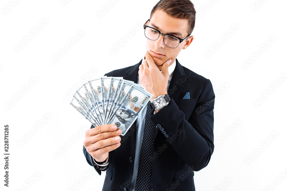 businessman in glasses and suit, holding dollar bills, looks at them carefully, on a white background. businessman in glasses and suit, holding dollar bills, looks at them carefully, on a white background.
