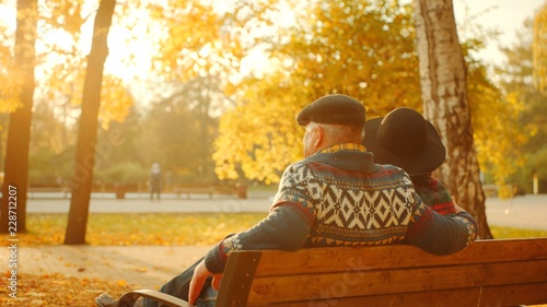 Senior couple enjoying sunset on the bench in the autumn park