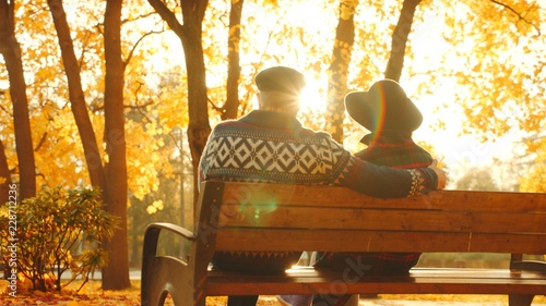Senior couple enjoying sunset on the bench in the autumn park