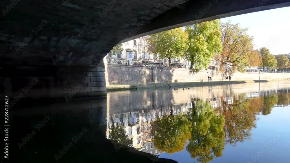 View under a bridge over the Ill River in Strasbourg, a city in eastern France. Reflection of the bridge arch in the water. Filmed on October 2018. View under a bridge over the Ill River in Strasbourg, a city in eastern France. Reflection of the bridge arch in the water. Filmed on October 2018.