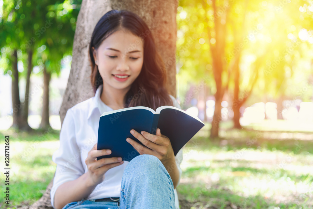 Beautiful woman reading a book on the grass of the park and enjoy learning she was happy to relax on holiday. Beautiful woman reading a book on the grass of the park and enjoy learning she was happy to relax on holiday.