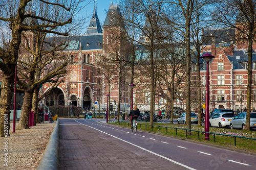 Cyclists at the bikeway next to the National Museum of Amsterdam in a cold early spring day